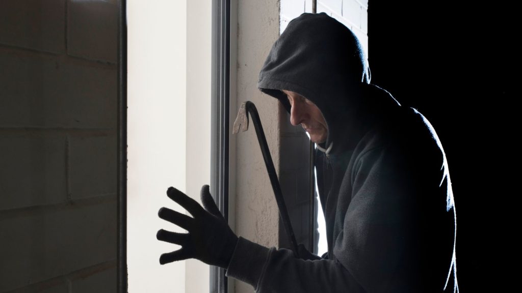 A burglar breaking in with a crowbar 