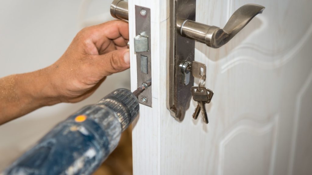 A homeowner demonstrates how to maintain door locks by tightening screws